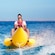 A man and a small child riding an inflatable watercraft shaped like a banana